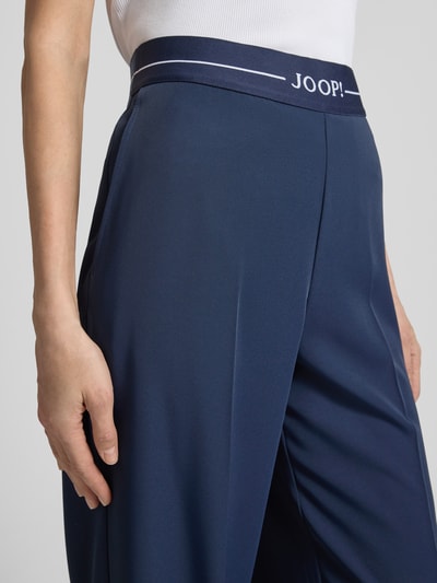 Kobiece model nosi Hose mit elastischem Bund und Label-Detail od JOOP!, mieszanka materiałów z dodatkiem streczu, krój regular fit, elastyczny pas, detal z logo, szerokość w rozmiarze 36: 38 cm, długość wewnętrzna nogawki 81 cm, zbliżenie na biodra