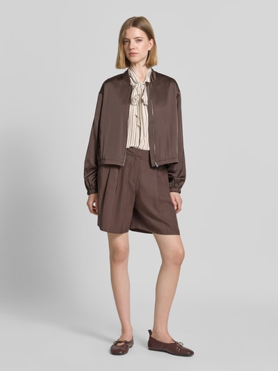 Frauenmodel trägt Slim Fit Schluppenbluse aus Viskose von comma mit Sportmanschetten und Teilungsnaht, cremefarben gestreift, kombiniert mit braunem Ensemble, Ganzkörperansicht von vorne.