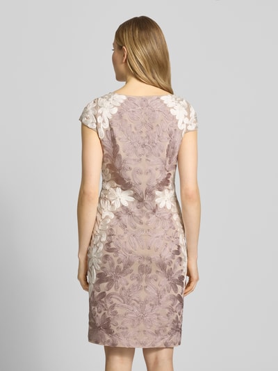 Frauenmodel trägt Knielanges Cocktailkleid mit Kappärmeln von Christian Berg Cocktail, florales Muster, Kappärmel, Körpernahe Passform, Elastischer-Material-Mix in zarten Rosatönen, Knielänge, Rückenlänge 95 cm, seitlicher Reißverschluss, Ganzkörperansicht Rückansicht.