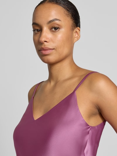 Vrouwenmodel draagt Blusentop aus Satin van Rinascimento in glanzende paarse Materiaalmix met stretch, getailleerde pasvorm, verstelbare spaghettibandjes, v-hals, ruglengte bij maat S 41 cm, detailopname van bovenlichaam.