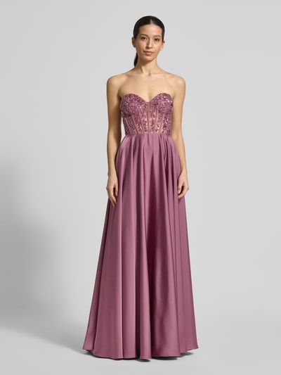 Modelka kobieca nosi Abendkleid mit Ziersteinbesatz od Laona w kolorze fioletowym, A-linia, dekolt serce, zdobienia z kamieni, długość do ziemi, szerokość w rozmiarze 36: 36 cm, długość pleców w rozmiarze 36: 130 cm, widok całej sylwetki z przodu.