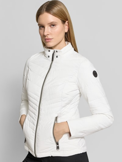 Frauenmodel trägt Slim Fit Jacke in Stepp-Optik von G.I.G.A. DX, weiß, Reißverschluss, Eingrifftaschen, Logo-Detail, Nahaufnahme Oberkörper.