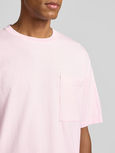 Männermodel trägt T-Shirt aus reiner Baumwolle mit Brusttasche Modell 'AFOMA' von American Vintage, hellrosa, Relaxed Fit, Nahaufnahme Oberkörper.