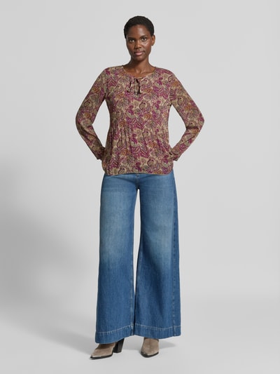 Frauenmodel trägt Relaxed Fit Bluse mit Allover-Paisley-Print Modell 'Leonora' von ZABAIONE in Creme und Pink, Ganzkörperansicht von vorne. Damen Bluse mit Zierschleife, langärmelig, Rückenlänge 65 cm, Ärmellänge 61 cm.