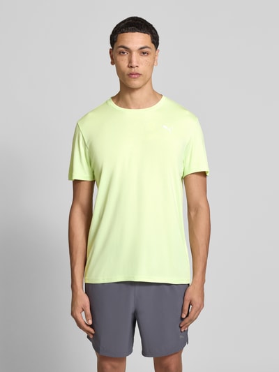 Männermodel trägt TRAINING T-Shirt mit Label-Detail Modell von PUMA PERFORMANCE in Hellgelb mit Rundhalsausschnitt, Gerader-Schnitt, Kurzärmelig, Rückenlänge 73 cm bei Größe M, Ganzkörperansicht von vorne.