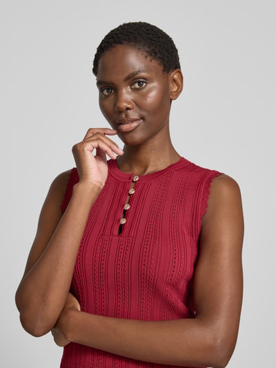 Frauenmodel trägt Stricktop in Pointelle-Strick mit kurzer Knopfleiste von GUESS, Viskose-Mix, Rundhalsausschnitt, Nahaufnahme Oberkörper.