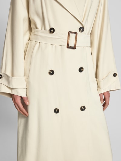 Vrouwenmodel draagt Mantel met Reverskraag van Jake*s Casual in crème, los model, tailleriem, knoopsluiting, steekzakken, mouwsluitingen, detailopname taille.