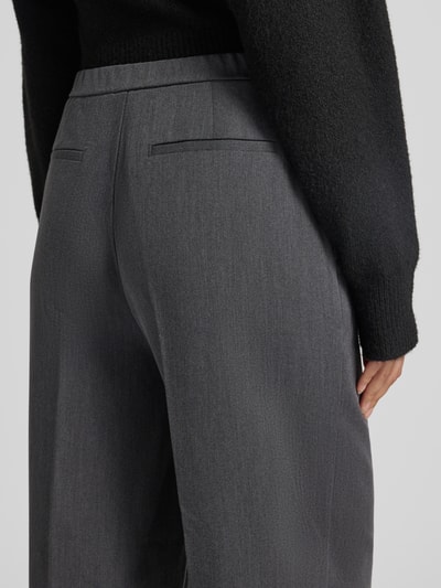 Frauenmodel trägt Bundfaltenhose mit Bügelfalten von OPUS in Grau, Viskosemix, matt, unifarben, Nahaufnahme Rückansicht.