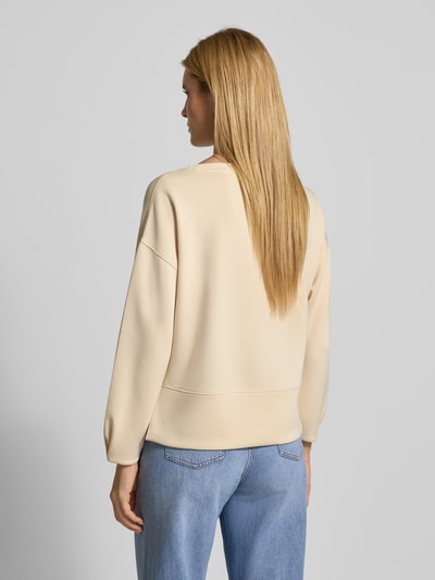 Frauenmodel trägt Relaxed Fit Sweatshirt mit Viskose-Anteil von comma, beige Farbe, U-Boot-Ausschnitt, verlängerte Rückseite, Ganzkörperansicht Rückansicht.