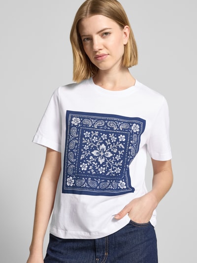 Frauenmodel trägt T-Shirt mit Motiv-Print und Ziersteinbesatz von Rich & Royal aus Reine Baumwolle, Regular-Fit, Rundhalsausschnitt, Weiß mit blauem Print, Rückenlänge bei Größe S 54 cm, Nahaufnahme Oberkörper.