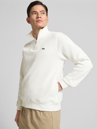 Männermodel trägt Regular Fit Troyer aus reiner Baumwolle von Lacoste, Optik: Unifarben, Logo-Patch, Strick, Ganzkörperansicht von vorne.