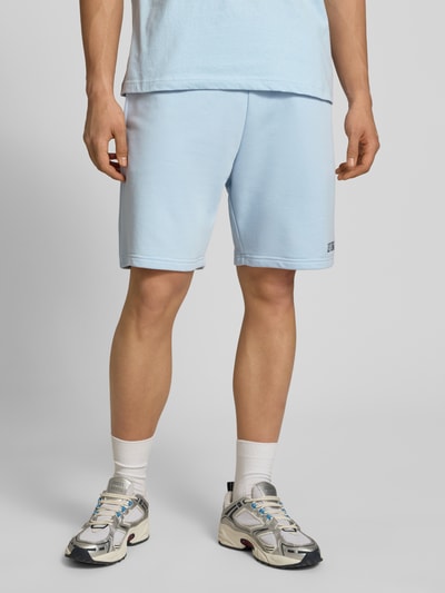 Männermodel trägt Regular Fit Shorts mit Label-Stitching von REVIEW aus Baumwoll-Mix in Hellblau, elastischer Bund, Nahaufnahme Oberschenkel.