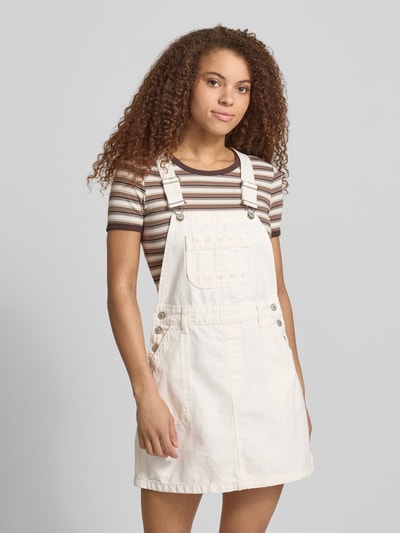 Frauenmodel trägt Leicht ausgestelltes Jeanskleid aus reiner Baumwolle von Tommy Jeans in Denim-Optik mit Mini-Länge, Karree-Ausschnitt, Label-Stitching-Applikation, Latzträger, Brusttasche und seitlichen Eingrifftaschen, Reine Baumwolle, Ganzkörperansicht von vorne.