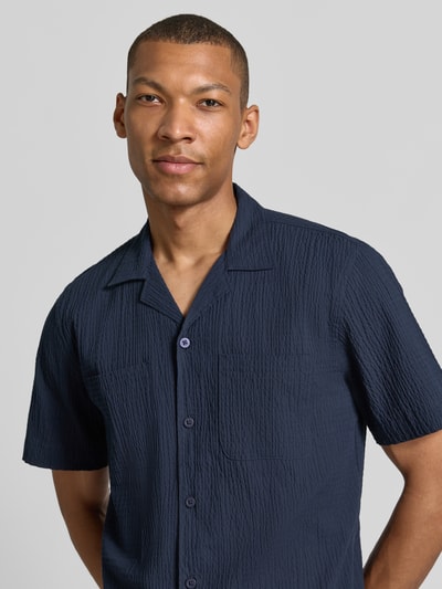 Männermodel trägt Modern Fit Freizeithemd mit Brusttaschen von Lindbergh, dunkelblauer Baumwoll-Mix mit Stretch-Anteil, Strukturmuster, Reverskragen, Knopfleiste, Nahaufnahme Oberkörper.