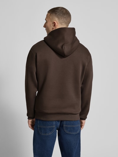 Männermodel trägt Hoodie mit Känguru-Tasche von REVIEW in Braun, lockere Passform, Baumwollmischung, Ganzkörperansicht Rückansicht.