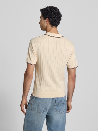 Męski model nosi Slim Fit Polo-Strickshirt mit Logo-Stickerei od REVIEW, czysta bawełna, krój slim fit, faktura prążkowana, widok całej sylwetki z tyłu.