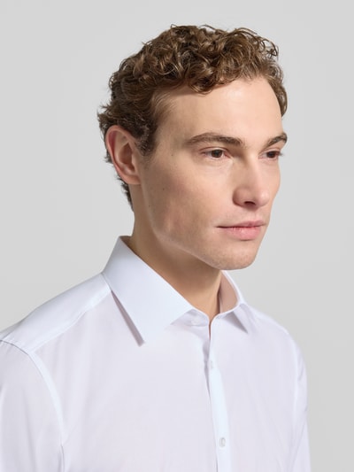 Męski model nosi Body Fit Business-Koszulę z listwą guzikową od OLYMP Level Five, mieszanka bawełny i elastanu, kołnierzyk typu kent, długość tyłu 80 cm, szerokość ramion 42 cm, długość rękawów 68 cm, biała, gładka faktura, z przodu zbliżenie na górną część ciała.