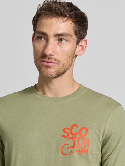 Männermodel trägt Regular Fit T-Shirt mit Logo-Print von Scotch & Soda in Olivgrün, reine Baumwolle, Nahaufnahme Oberkörper.