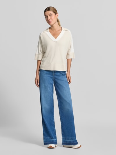 Frauenmodel trägt High Waist Bootcut Jeans mit breitem Saum von MARC CAIN in Medium Wash Denim mit 5-Pocket-Design, Ganzkörperansicht von vorne.
