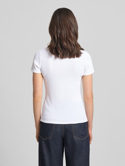 Vrouwenmodel draagt T-shirt met Label-Detail van Marc Cain, elastische materiaalmix, nauwsluitend model, u-hals, ruglengte maat 36: 55 cm, geheel witte kleur, gestructureerde textuur, denim broek, geheellichaamsaanzicht rugaanzicht
