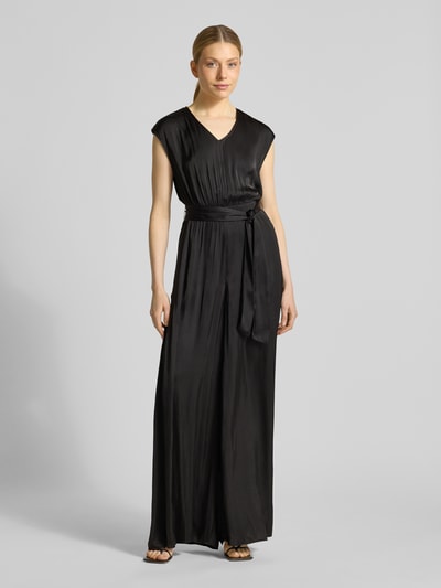 Kobiece model prezentuje Regular Fit Jumpsuit mit Taillengürtel zum Binden od s.Oliver RED LABEL, efekt: jednolity kolor, krój regular fit, dekolt w serek, zamek błyskawiczny, bez rękawów, wpuszczane kieszenie, wykończenie materiału: satyna, czarny, gładka tekstura, całkowity widok z przodu.