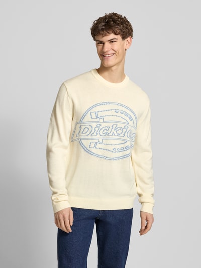 Männermodel trägt Strickpullover mit Logo und Rundhalsausschnitt von Dickies in Creme mit blauem Schriftzug, Regular Fit, Nahaufnahme Oberkörper.