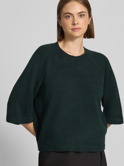 Kobieta modelka nosi ciemnozielony sweter z rękawami o dł. 3/4, model 'SIMONI' od ONLY, damski sweter, z przodu zbliżenie na górę ciała.
