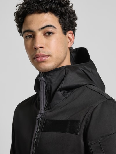 Männermodel trägt Regular Fit Regenjacke mit Reißverschluss Modell 'Batt' von G-Star Raw, schwarze glatte Oberfläche, Nahaufnahme Oberkörper.