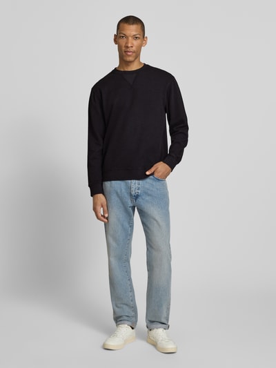 Männermodel trägt Regular Fit Sweatshirt mit ronde hals van Scotch & Soda, katoenmix, labeldetail, ruglengte maat M 68 cm, mouwlengte maat M 65 cm, ganzlichaamsaanzicht van voren.