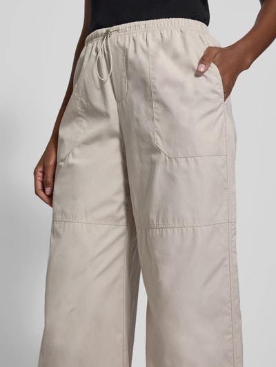 Frauenmodel trägt Stoffhose mit elastischem Bund von black palms, Reine Baumwolle, Lockerer-Schnitt, Tunnelzug, Eingrifftaschen, Nahaufnahme Oberkörper.