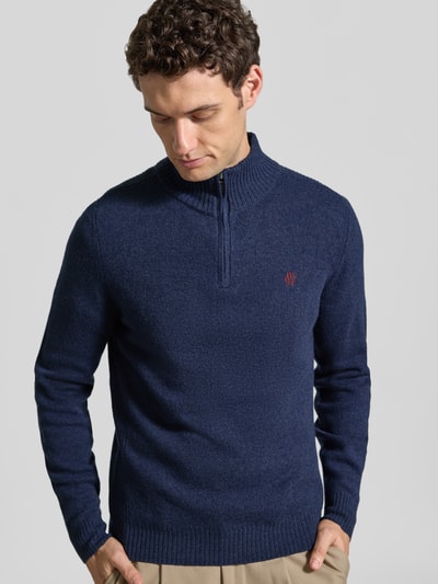 Männermodel trägt Regular Fit Strickpullover aus reiner Wolle von MCNEAL in Dunkelblau mit Logo-Stickerei, Ganzkörperansicht von vorne.