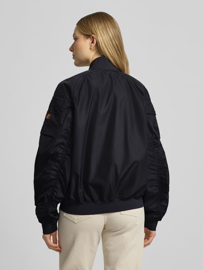 Frauenmodel trägt dunkelblaue Bomberjacke mit Reißverschlusstaschen Modell 'LIL' von SAVE THE DUCK, Material-Mix mit Stretch-Anteil, Regular-Fit, Ganzkörperansicht Rückansicht. Rückenlänge bei Größe S: 53 cm, Schulterbreite: 42 cm, Brustweite: 61 cm, Ärmellänge: 70 cm.