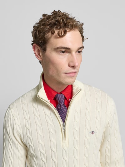 Männermodel trägt Strickpullover mit gerippten Abschlüssen von Gant, Reine Baumwolle, Slim-Fit, Stehkragen, Reißverschluss, Label-Stitching, Nahaufnahme Oberkörper.