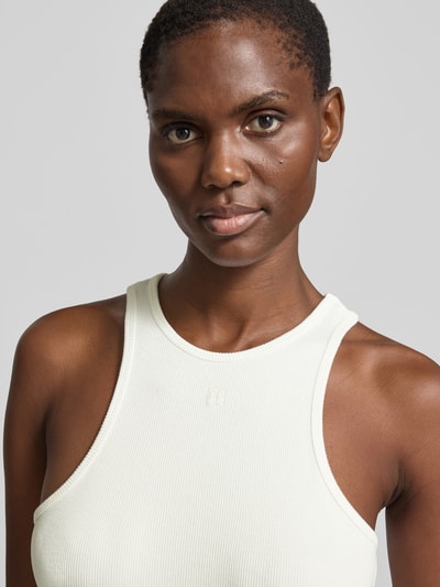 Frauenmodel trägt Slim Fit Top aus Viskose-Mix von Anine Bing in Creme mit Strukturmuster, Rundhalsausschnitt, Ärmelloses-Design, Nahaufnahme Oberkörper.