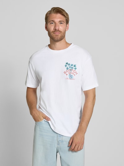 Männermodel trägt Regular Fit T-Shirt aus reiner Baumwolle von Scotch & Soda in Weiß mit Label-Print, Nahaufnahme Oberkörper. Rückenlänge Größe M: 68 cm.