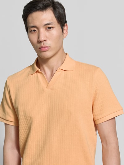 Männermodel trägt Regular Fit Strick-Poloshirt mit V-Ausschnitt von MCNEAL in Pfirsich, Baumwoll-Mix mit Stretch-Anteil, Nahaufnahme Oberkörper.