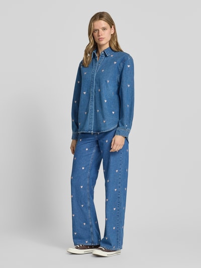 Frauenmodel trägt Loose Fit Wide Leg Jeans aus reiner Baumwolle Modell 'VEGA' von Only mit Motiv-Stitching und 5-Pocket-Design in Denim-Optik, High-Waist-Stil, Gürtelschlaufen sowie Knopf und verdecktem Reißverschluss; Ganzkörperansicht von vorne.