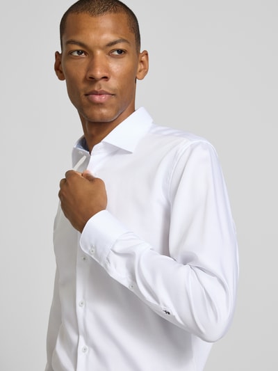 Mannelijk model draagt wit slim fit zakelijk overhemd van katoen Slim Fit Businesshemd aus reiner Baumwolle van Seidensticker, close-up bovenlichaam.