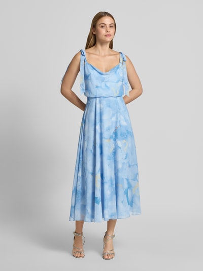 Frauenmodel trägt Knielanges Cocktailkleid mit floralem Allover-Print von Jake*s Cocktail in Hellblau mit Zierschleifen, Taillierter Passform, Blickdichtem Unterrock, Ärmellosem-Design und floraler Textur, Ganzkörperansicht von vorne. Rückenlänge bei Größe 36: 102 cm, Brustweite 40 cm.