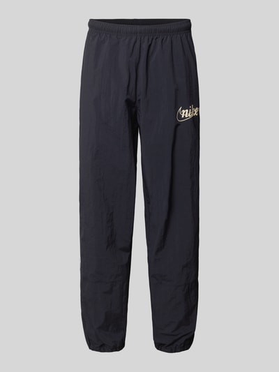 Produktfoto, Trainingshose mit Logo und elastischem Bund von Nike in Schwarz, Relaxed-Fit, Logo-Print, elastische Beinabschlüsse, Innenbeinlänge bei Größe M: 76 cm.
