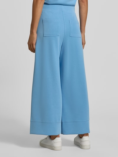 Frauenmodel trägt Wide Leg Sweatpants aus Modal-Mix von Rich & Royal in Hellblau mit elastischem Bund, Bundfalten und Gesäßtaschen, Ganzkörperansicht Rückansicht.