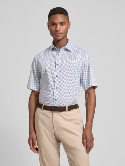 Männermodel trägt Regular Fit Business-Hemd mit Kentkragen von OLYMP, weiß-blau kleingemustert aus Baumwolle, Nahaufnahme Oberkörper.