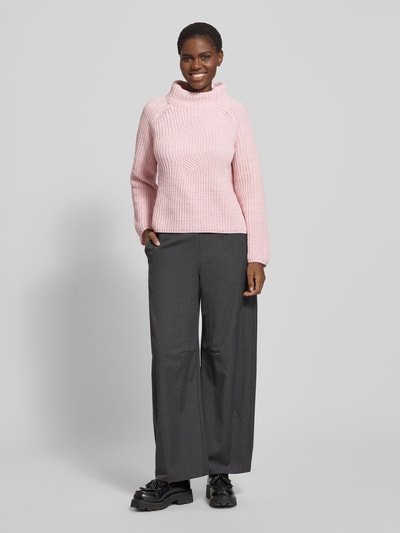 Frauenmodel trägt Sweter z dzianiny o kroju regular fit monari z wyraźną fakturą, stójka, kolor jasnoróżowy, model 'Basic Chenille', gruby ścieg, długość tyłu 61 cm, długość rękawów 56 cm, Ganzkörperansicht von vorne.