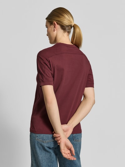 Vrouwenmodel draagt T-Shirt met Label-Print van Anine Bing in bordeauxrood van pure katoen, rechte fit, ronde hals, ruglengte maat S 58 cm, volledige lichaamsweergave achteraan.