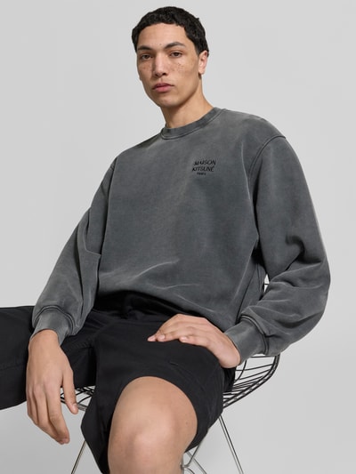 Männermodel trägt Oversized Hoodie aus Baumwoll-Mix von MAISON KITSUNÉ in Grau mit Rundhalsausschnitt, elastischen Abschlüssen, Used-Look, Ganzkörperansicht von vorne