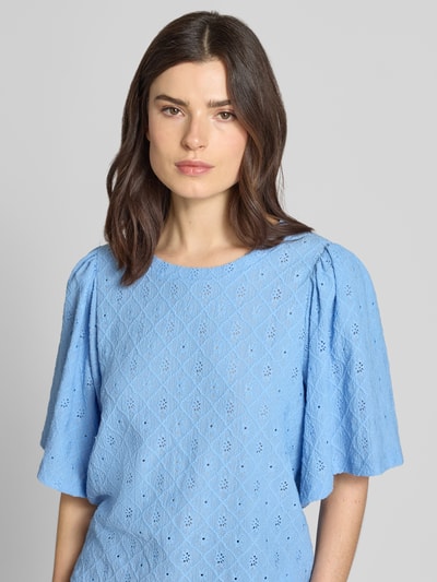 Frauenmodel trägt Blusenshirt mit Lochstickerei Modell 'KIONA' von FREE/QUENT, hellblau, Material-Mix mit Stretch-Anteil, Rundhalsausschnitt, Regular-Fit, Nahaufnahme Oberkörper. Rückenlänge bei Größe S: 55 cm, Ärmellänge: 33 cm.