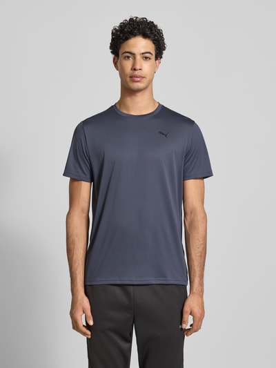 Männermodel trägt Regular Fit T-Shirt mit Logo-Print Modell 'Solid' von PUMA PERFORMANCE mit Rundhalsausschnitt, Ganzkörperansicht von vorne. Rückenlänge bei Größe M: 70 cm. T-Shirt einfarbig dunkelgrau mit glatter Textur.