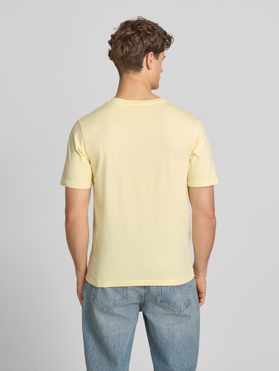 Männermodel trägt T-Shirt mit Label-Print Modell 'CASSIS' von Jack & Jones aus Reine Baumwolle, Regular-Fit, Rundhalsausschnitt, Rückenlänge 68 cm, sanftgelber Ton, glatte Struktur, Ganzkörperansicht Rückansicht.