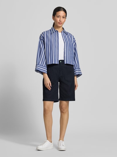 Frauenmodel trägt Chino-Shorts mit Gesäßleistentaschen von Buena Vista aus dunkelblauem Baumwoll-Mix mit Stretch-Anteil, Wide-Fit, Knopf- und Reißverschluss, seitlichen Eingrifftaschen, Bundweite bei Größe S 40 cm, Innenbeinlänge 25 cm, Ganzkörperansicht von vorne.