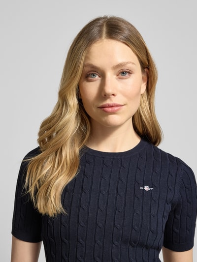 Frauenmodel trägt Strickshirt mit Zopfmuster und Label-Stitching von Gant, dunkelblau, Baumwoll-Mix, Nahaufnahme Oberkörper.